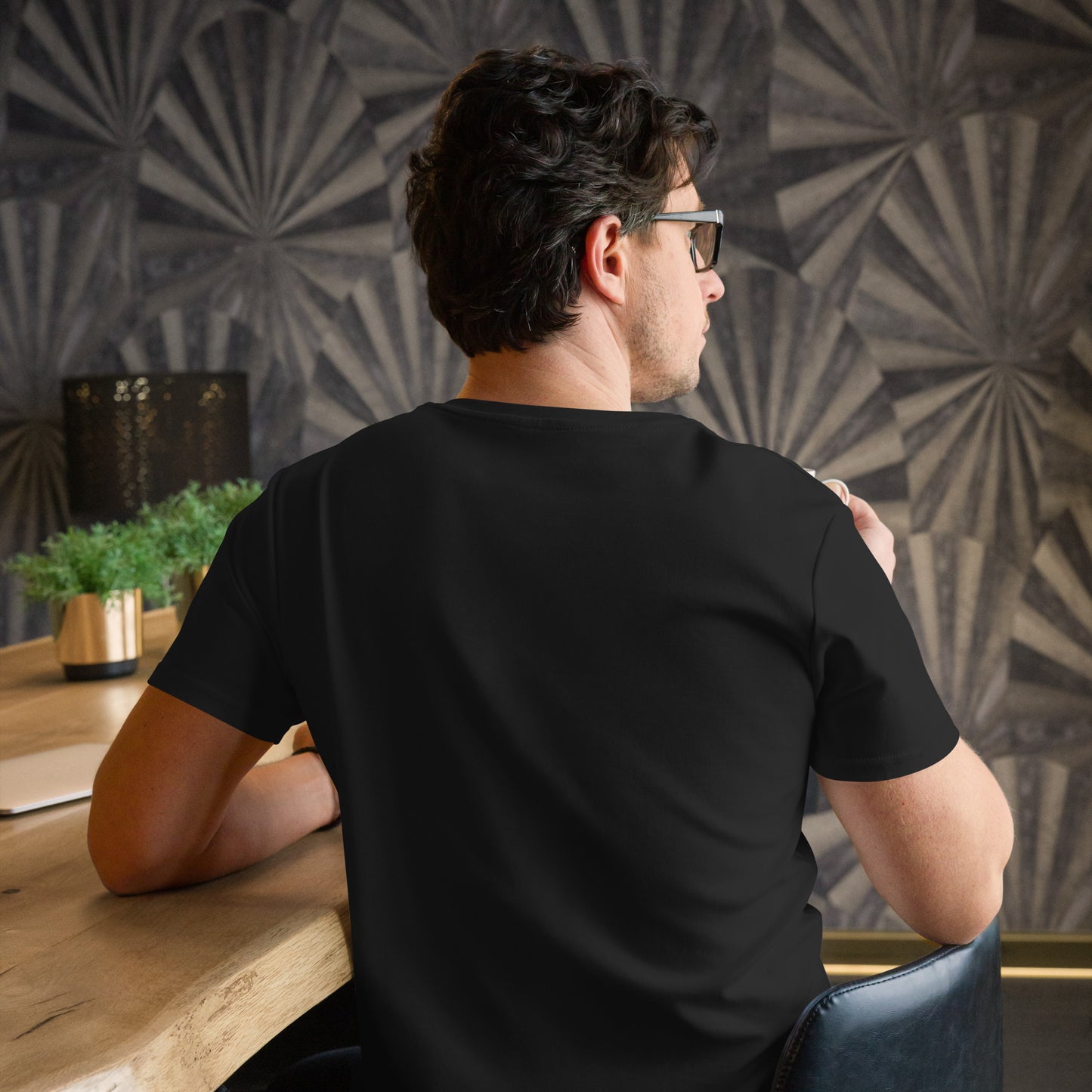 Man wearing a comfortable men's fashion t-shirt by PJ Designs sitting at a wooden table indoors