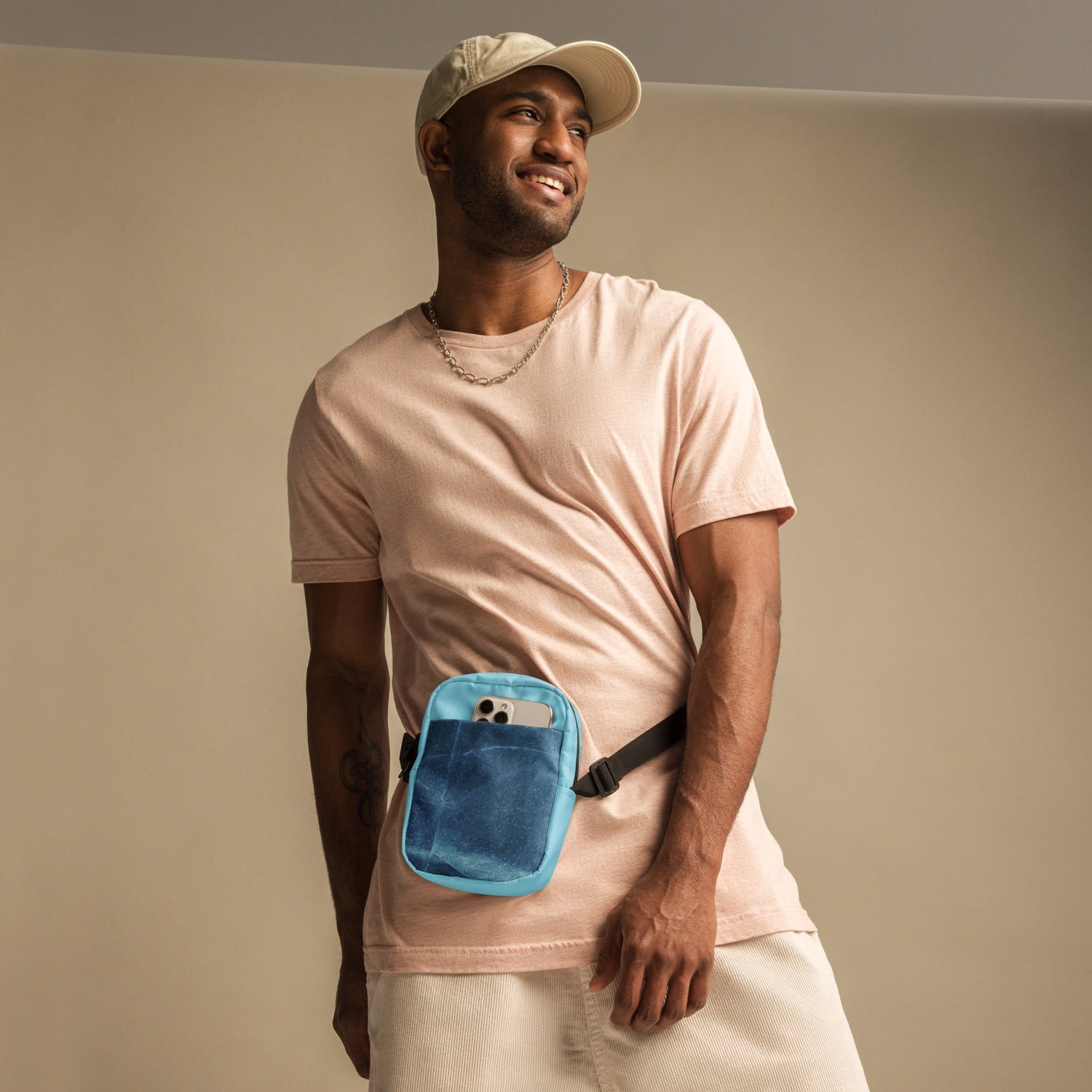 Smiling man wearing a beige cap and pink shirt with a blue trendy unisex bags waist pouch
