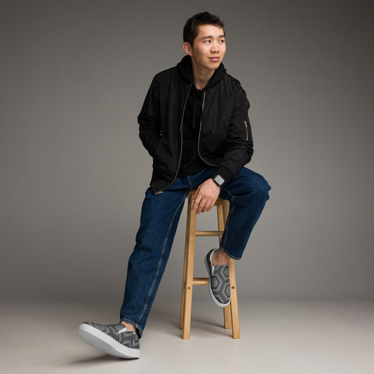 Man wearing PJ Designs comfortable men's slip-on loafers in gray while sitting on a wooden stool