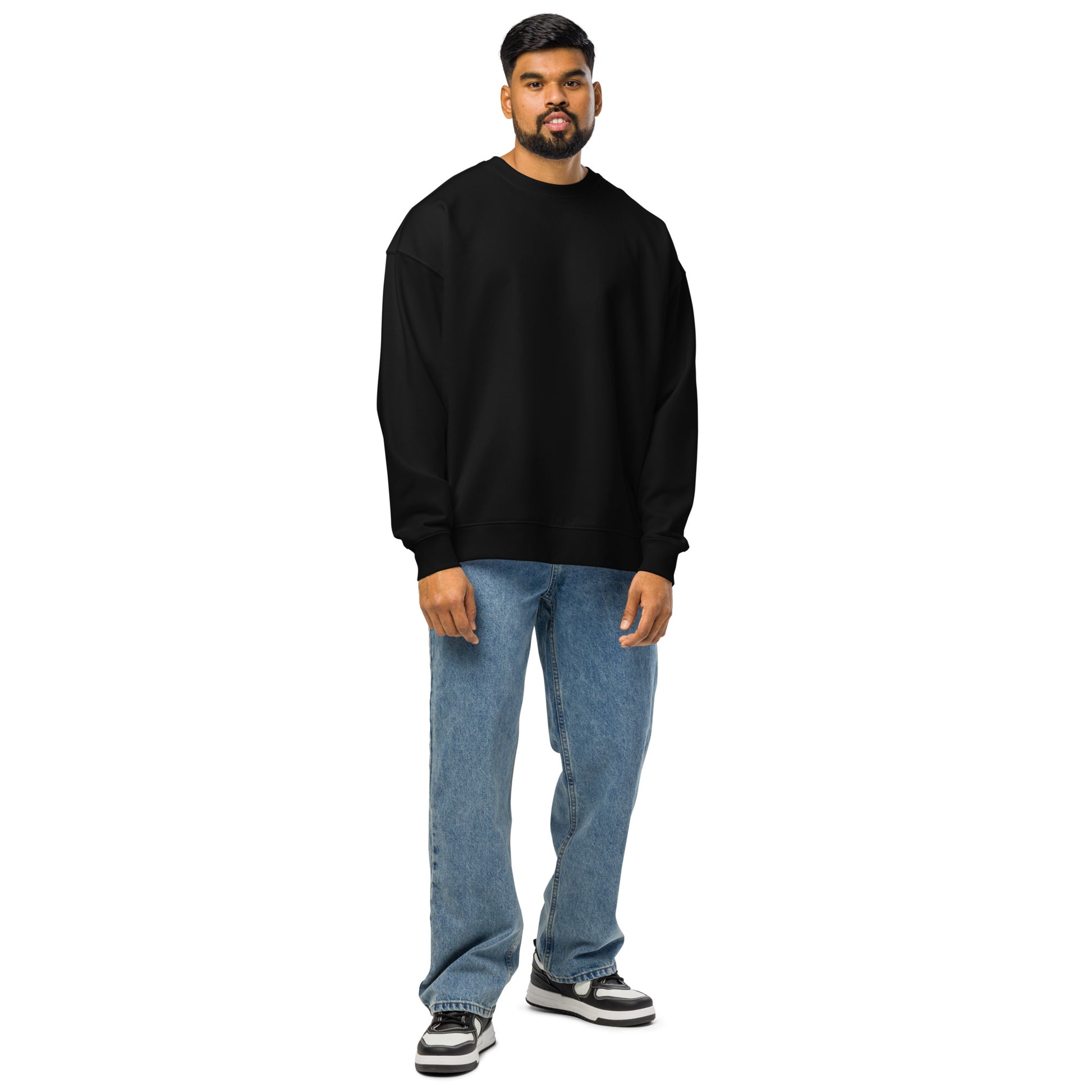 Man wearing black comfortable oversized crewneck sweatshirt paired with blue jeans and sneakers