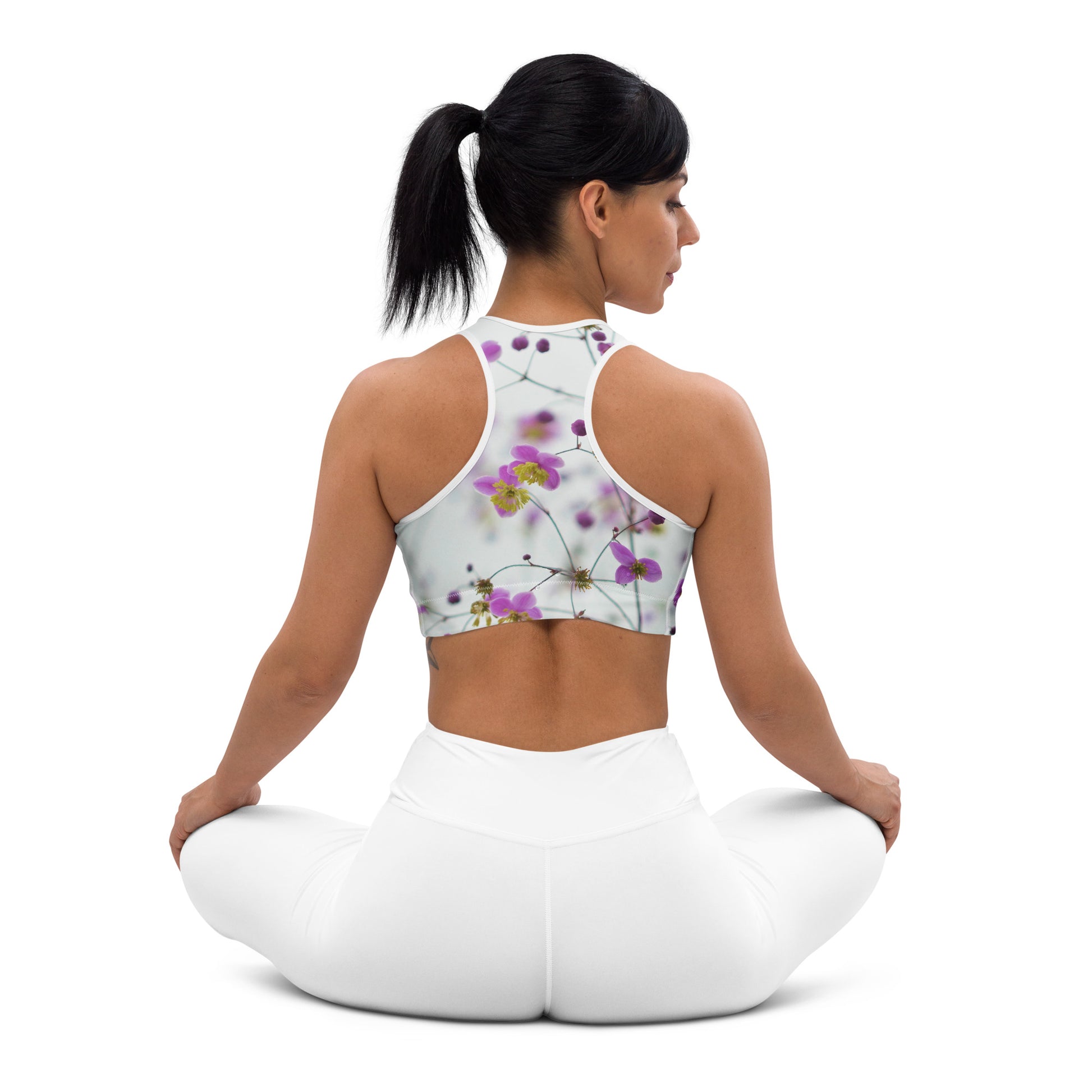 Woman wearing floral sports bra with padding from PJ Designs sitting cross-legged in white leggings