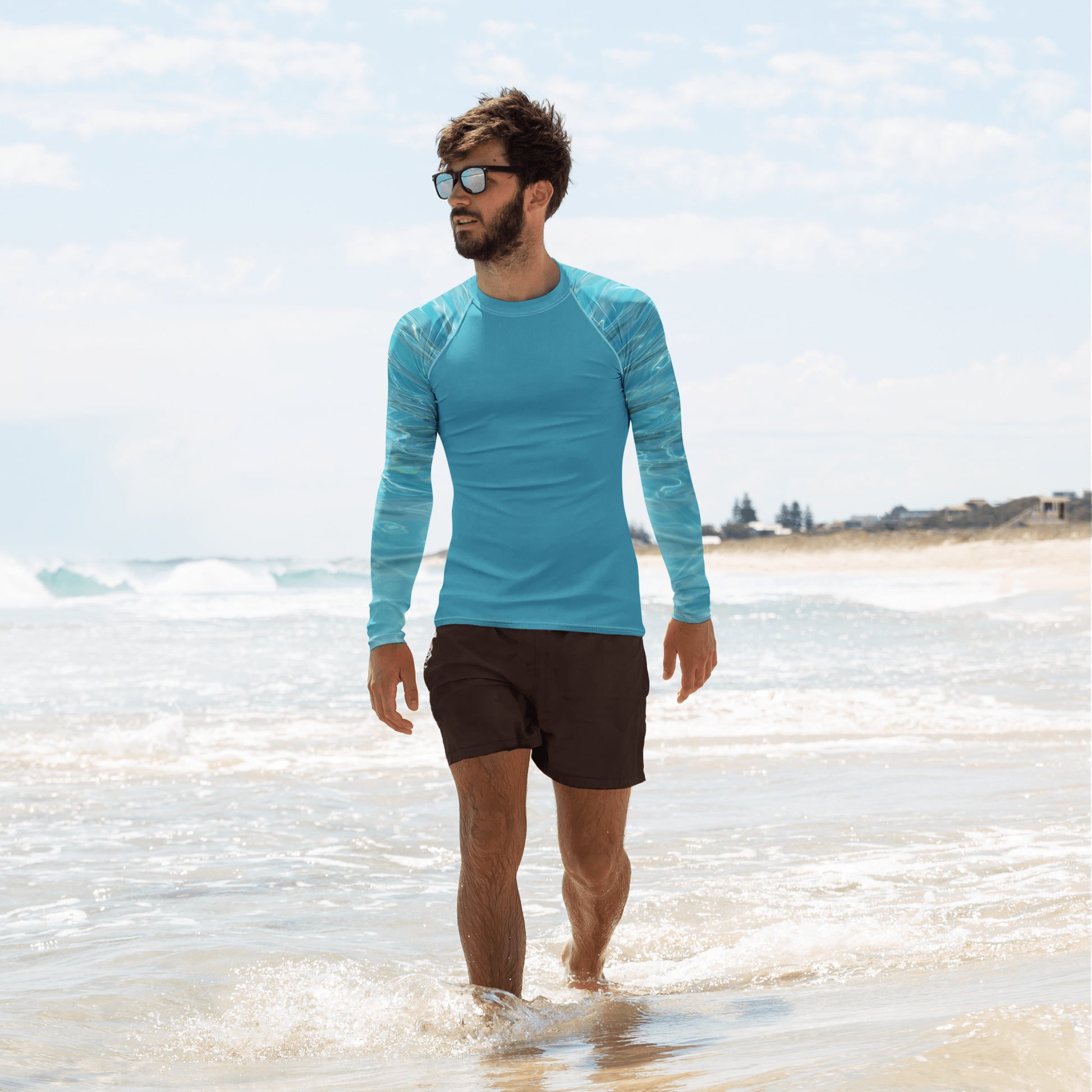 Man wearing a blue athletic swim top for men by PJ Designs walking in the ocean shallow water