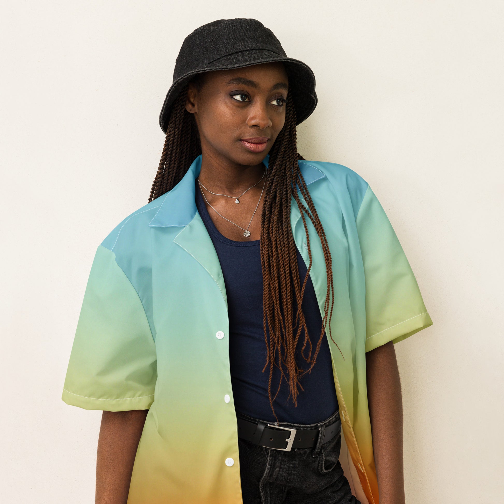PJ Designs summer short sleeve unisex shirt with gradient blue to green to orange colors worn by a model with a black bucket hat