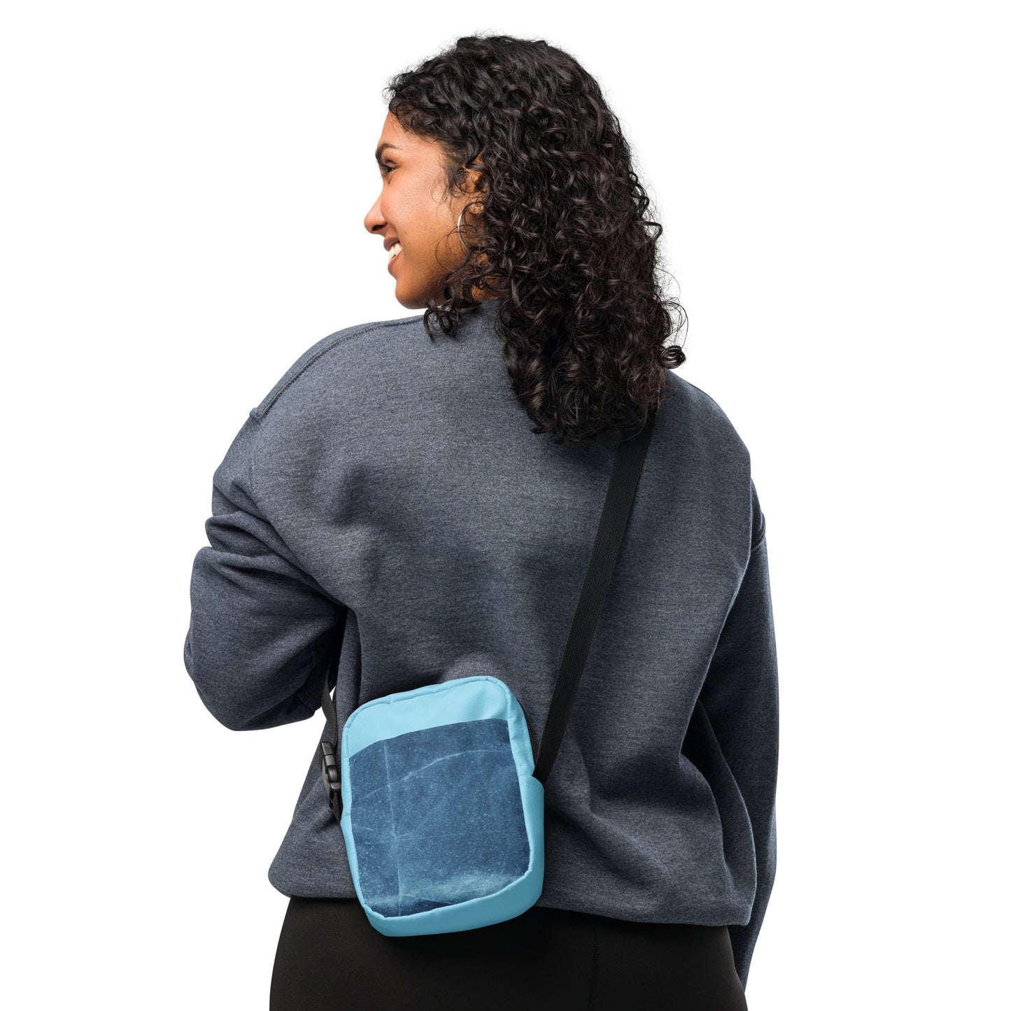 Woman wearing a blue PJ Designs unisex streetwear bag with adjustable black strap over grey sweatshirt